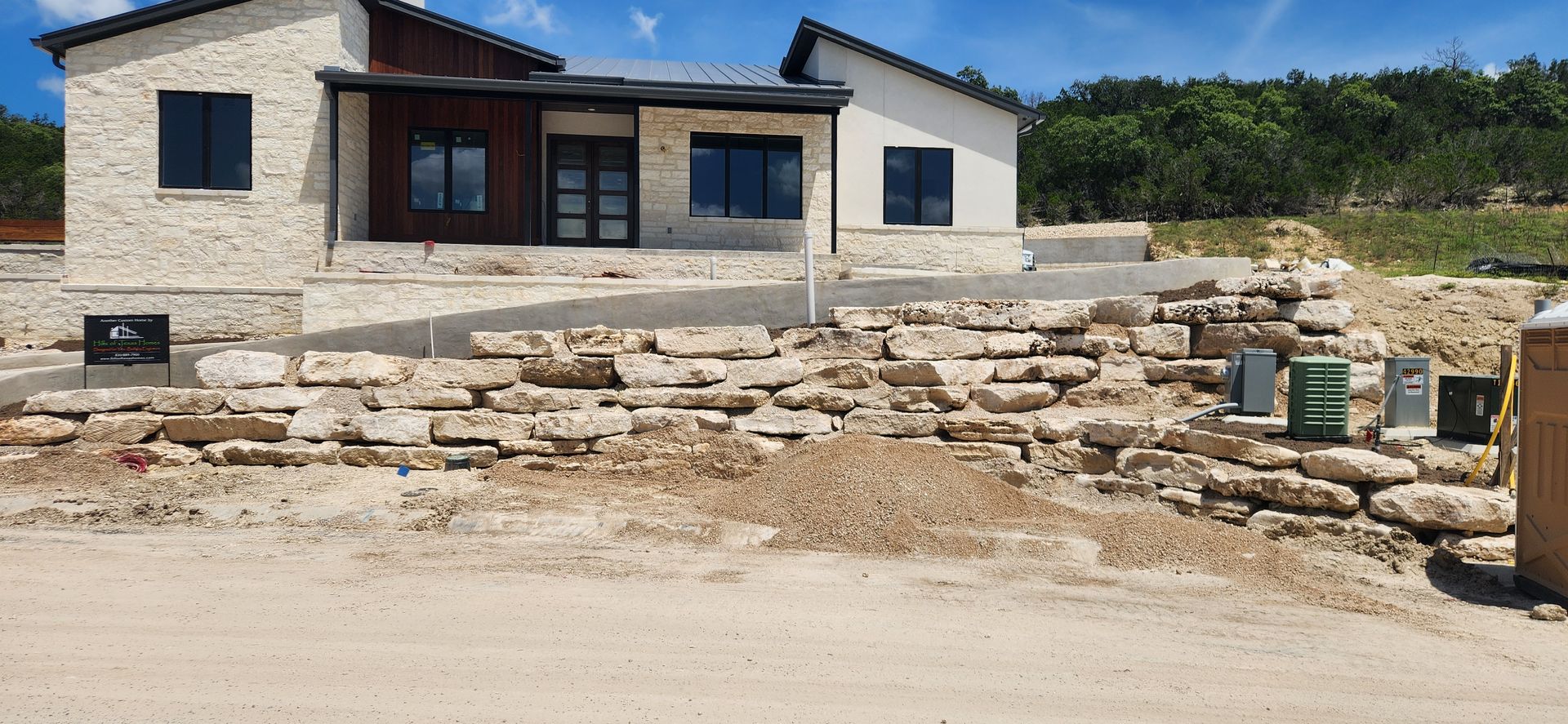 Stone house under construction with unfinished front yard and scattered building materials