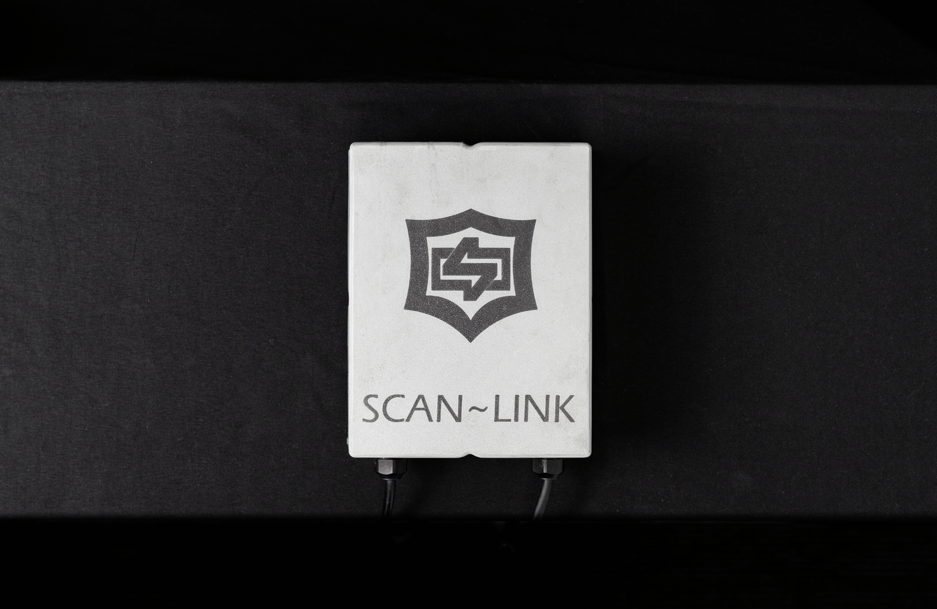 Black Scan-Link device with a circular green light display, red button, and cable.