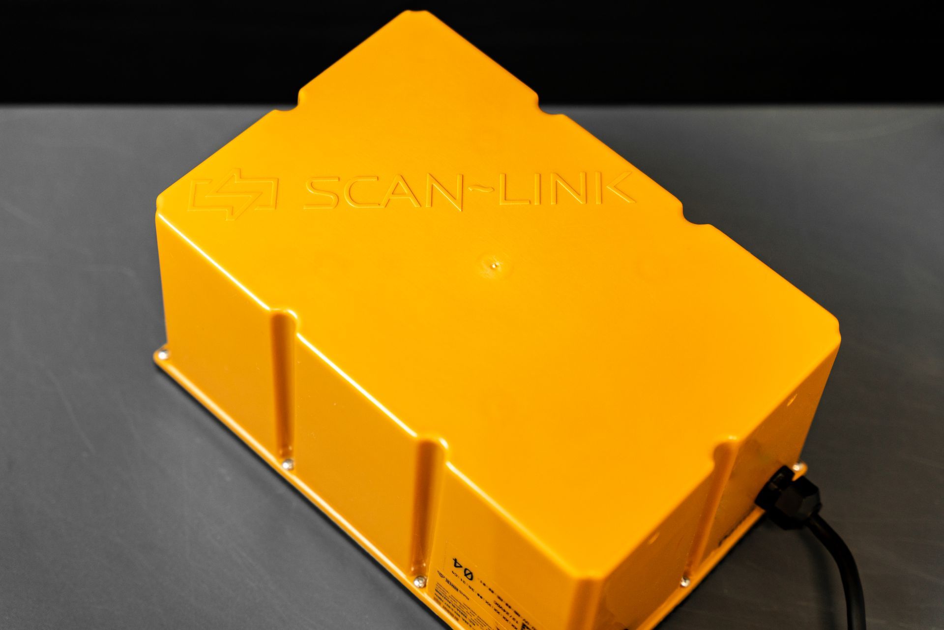 Black Scan-Link device with a circular green light display, red button, and cable.