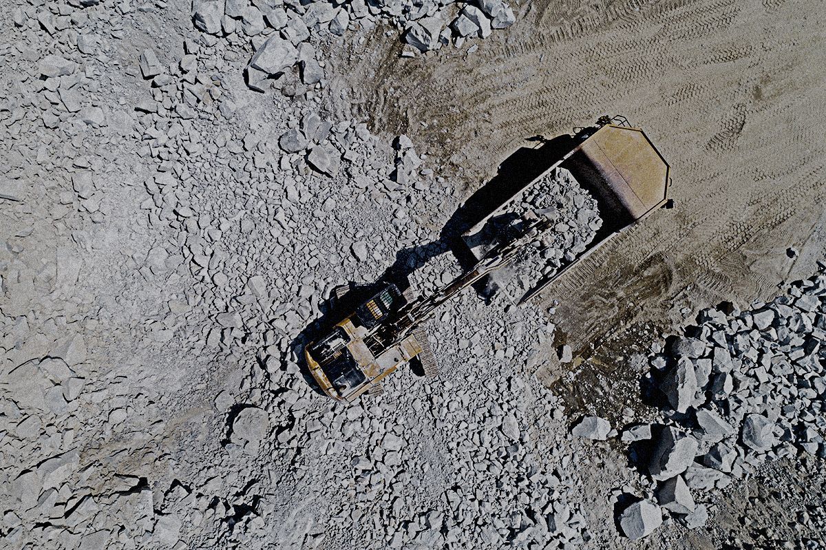 An aerial view of a bulldozer moving rocks in a quarry.