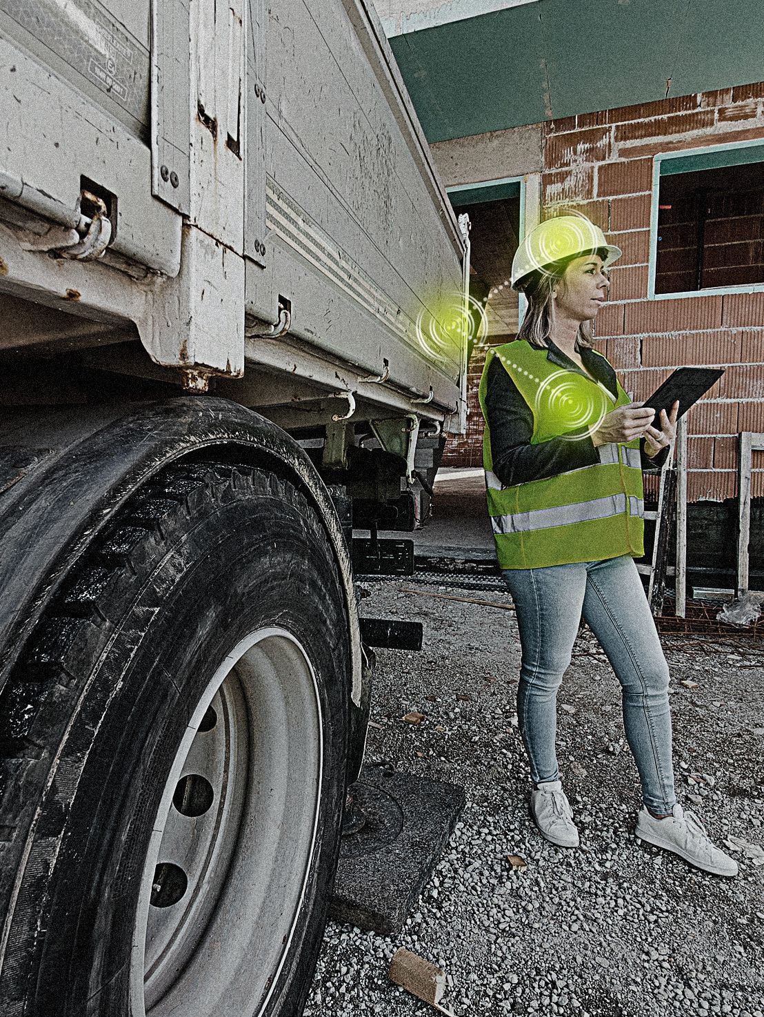 A woman wearing a hard hat and safety vest is standing next to a truck.