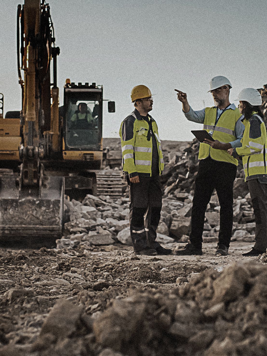 A group of construction workers are standing in front of an excavator.