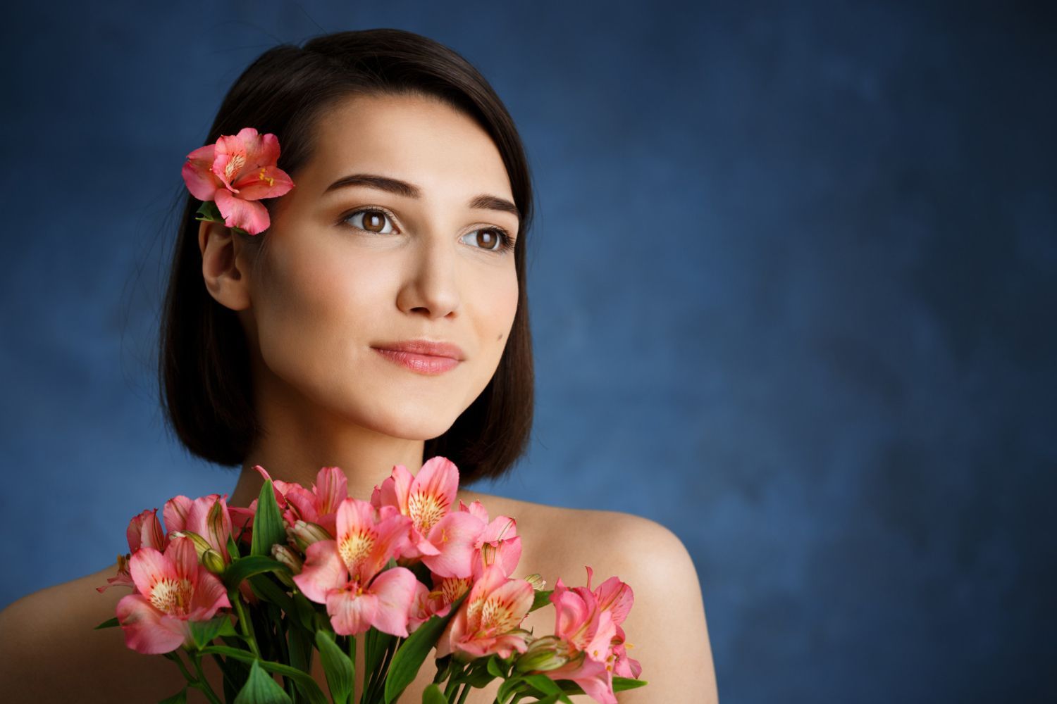 A woman is holding a bouquet of pink flowers in her hand.