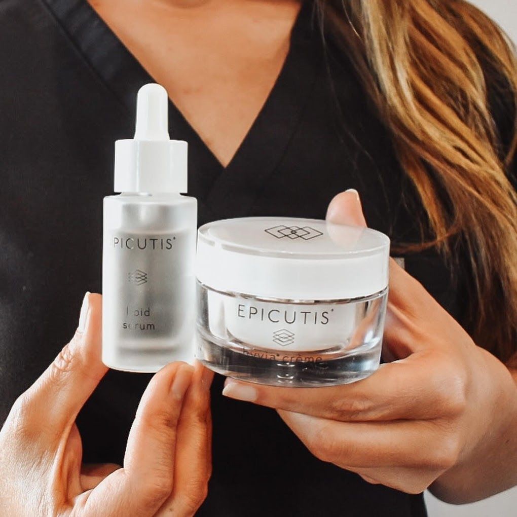 A woman is holding a bottle of epicutis serum and a jar of epicutis cream