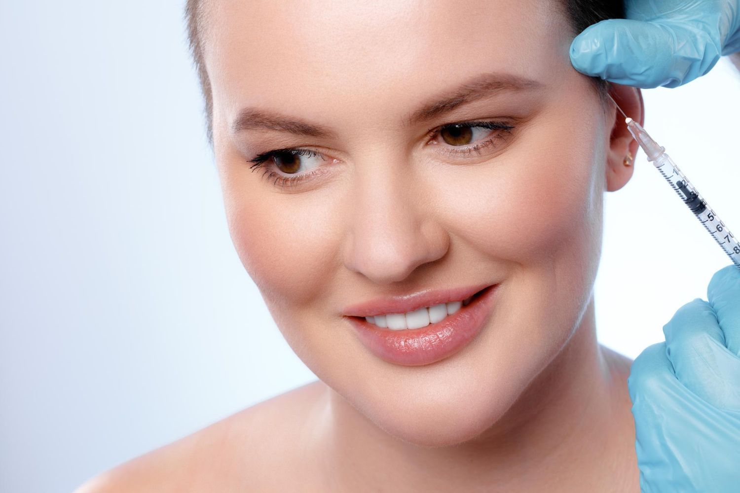 A woman is getting a botox injection in her forehead.