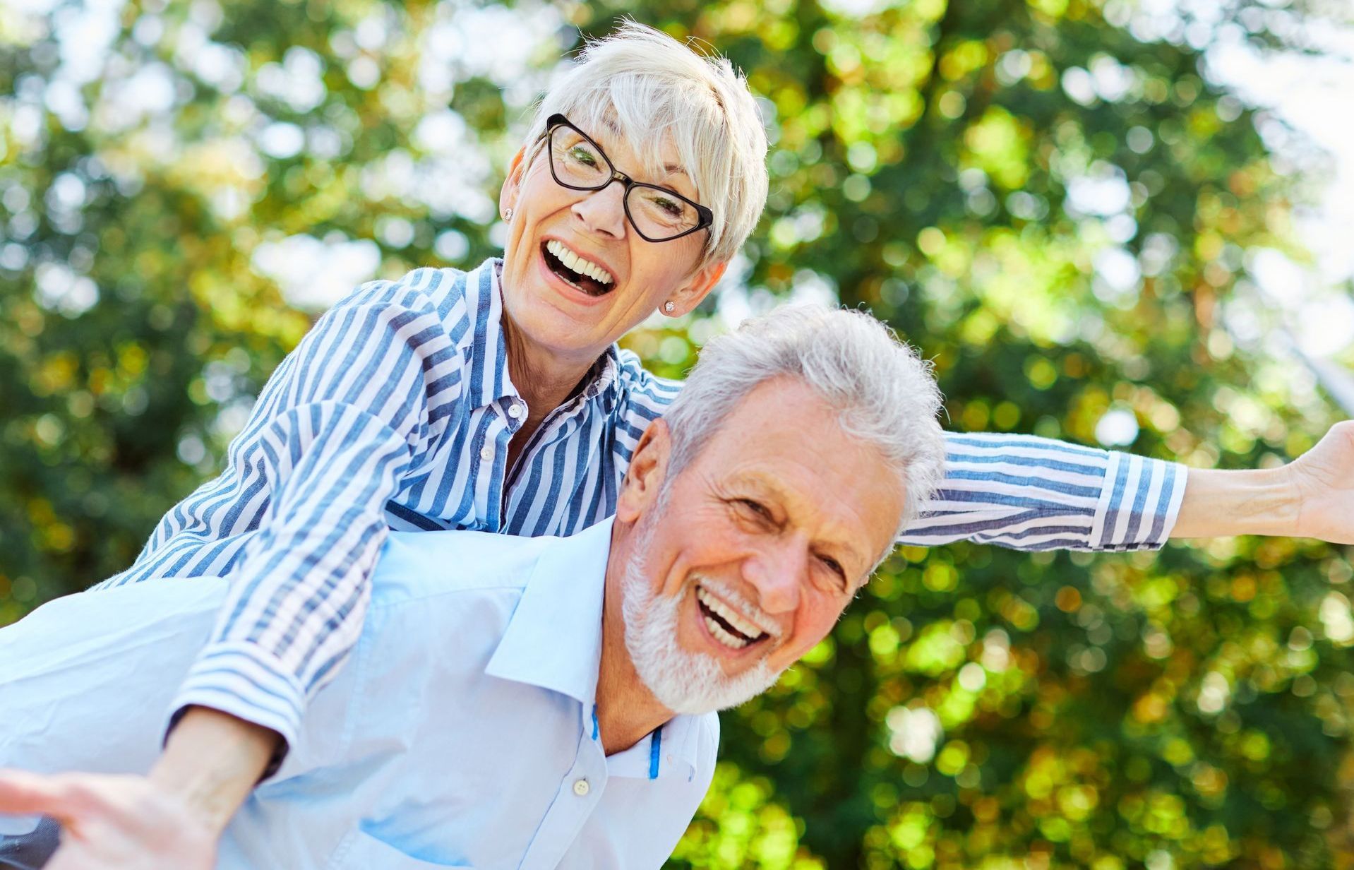 A man is giving a woman a piggyback ride in a park.