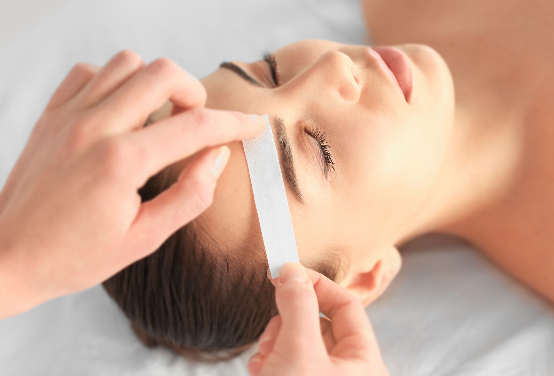 A woman is getting her eyebrows waxed at a beauty salon.