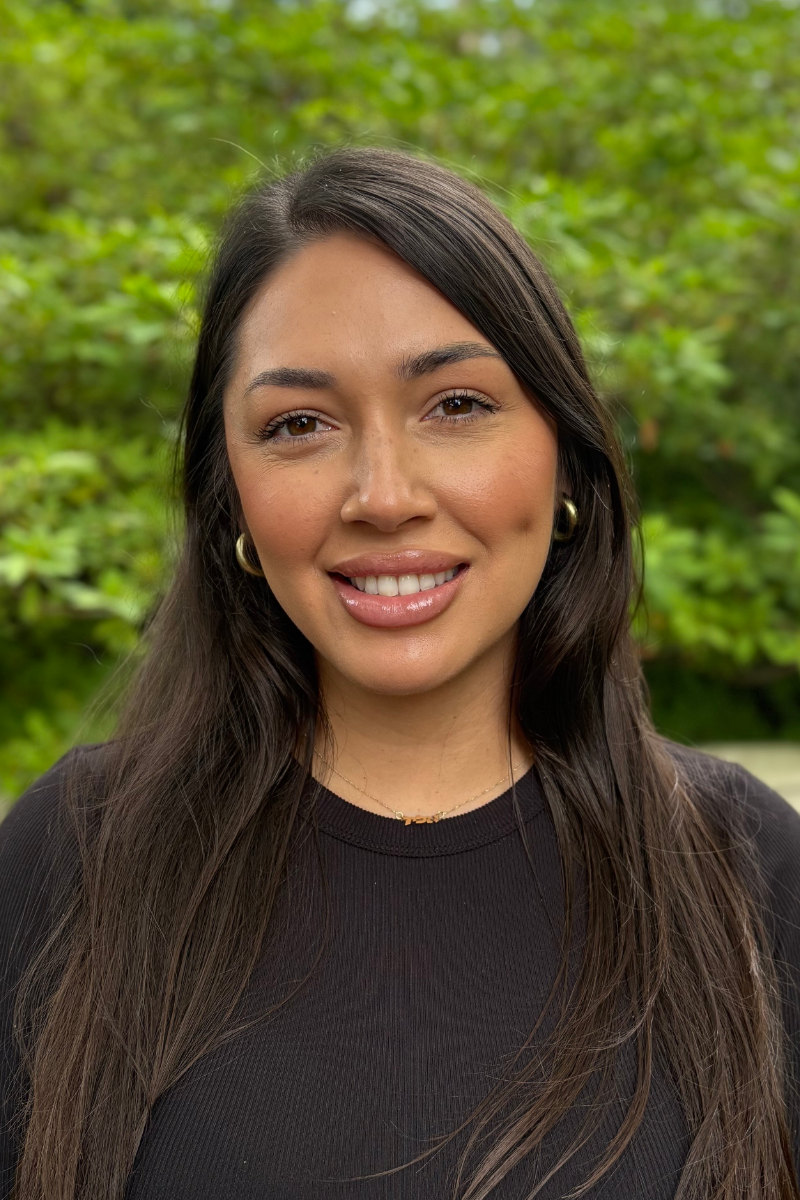 A woman with long black hair is smiling for the camera