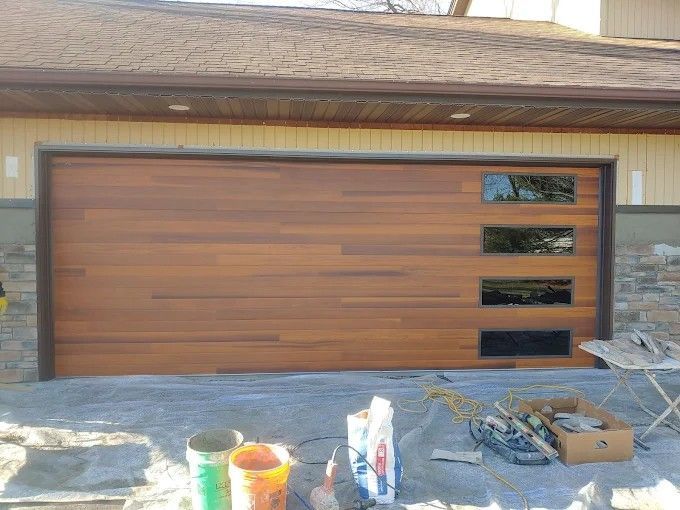 A wooden garage door is being installed on a house.