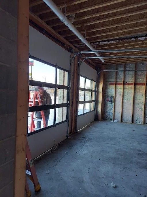 A man is standing in an empty room with a ladder.