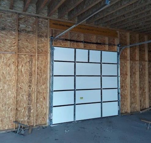 A white garage door is open in a building under construction