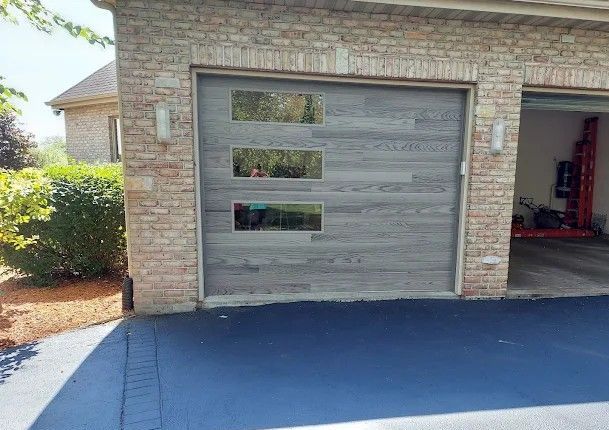 A brick garage with a wooden garage door and a blue driveway.