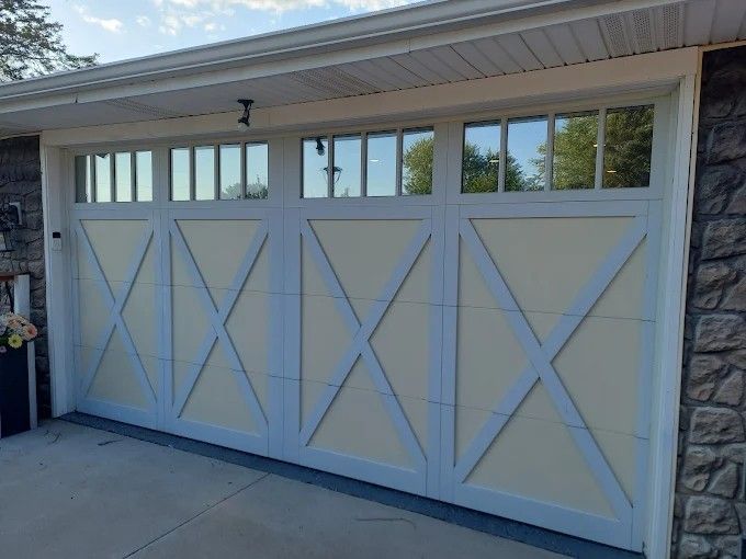 A white garage door with a lot of windows is sitting on the side of a house.