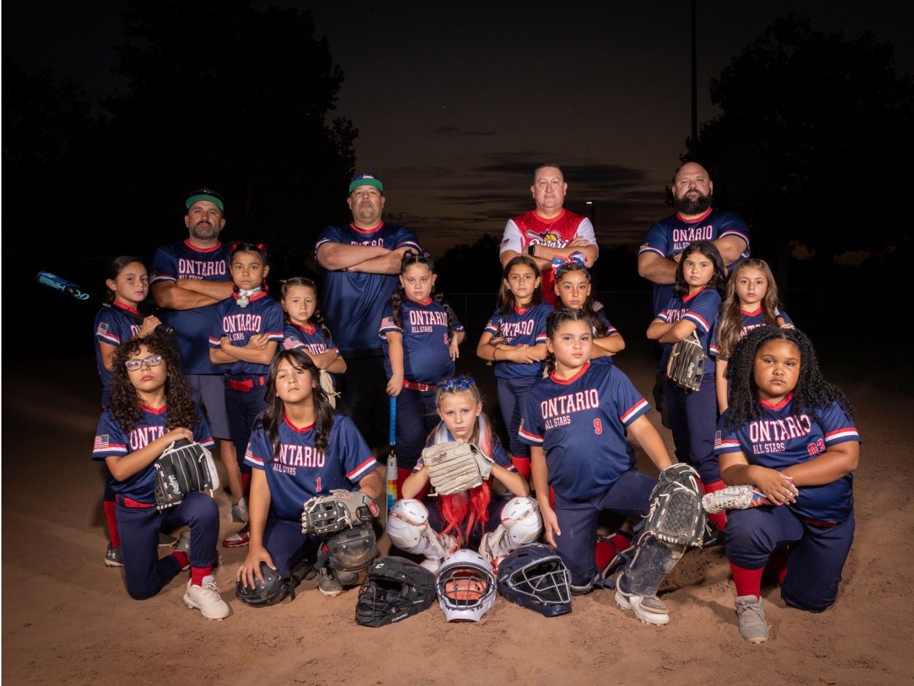 Baseball glove with ball on green grass, with blurred baseballs in the background.