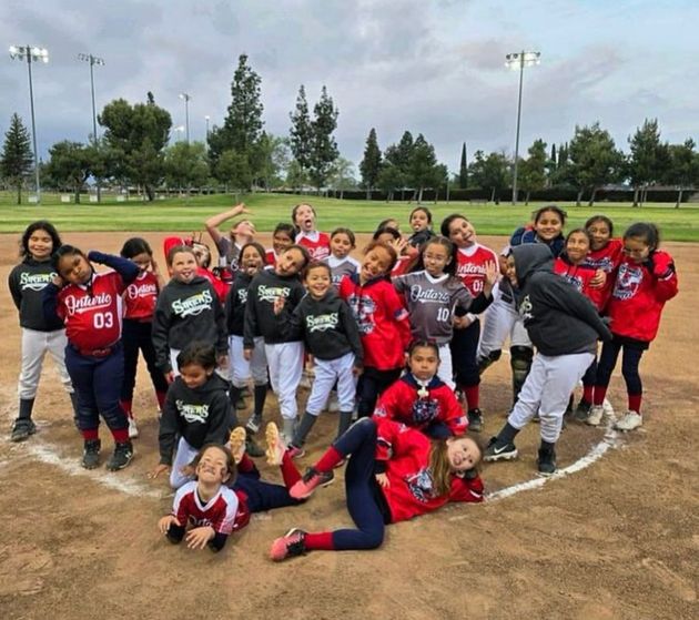Baseball player sliding into home plate, catcher in front. Blue and gold uniforms, action shot.