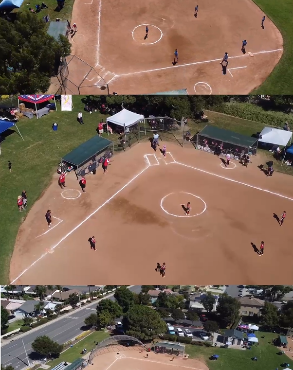 A person wearing a hat and orange shirt, holding a baseball bat on their shoulder on a baseball field.