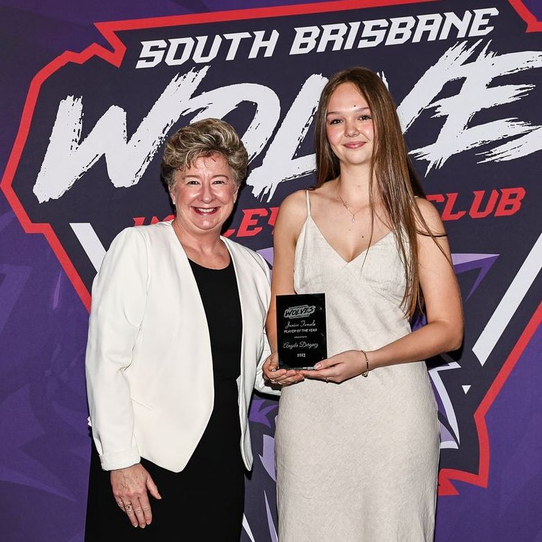 Two women standing in front of a sign that says south brisbane wolves
