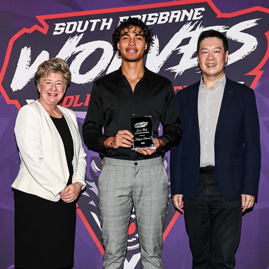 Three people standing in front of a sign that says south brisbane wolves