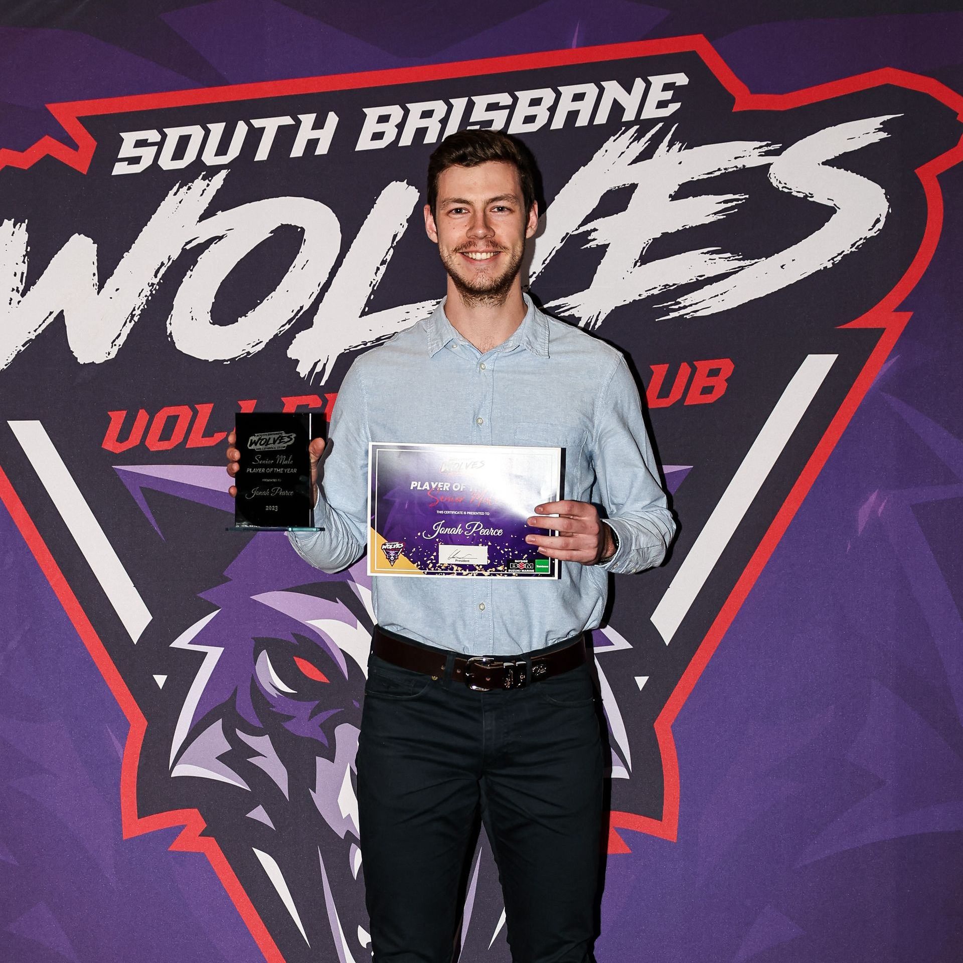 A man holding a certificate in front of a south brisbane wolves logo