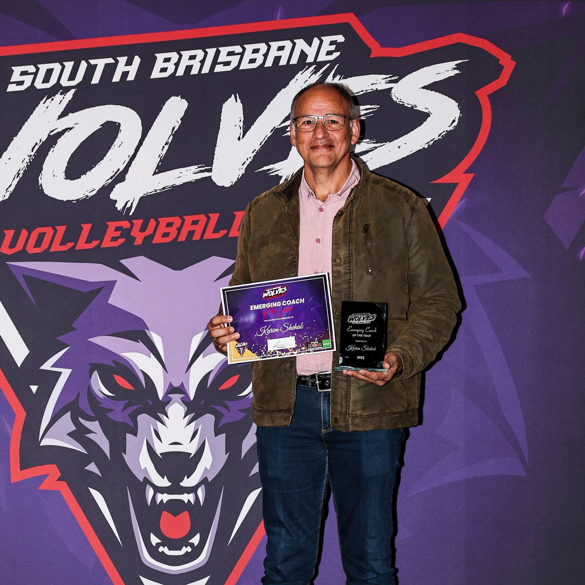A man holding an award in front of a south brisbane wolves logo