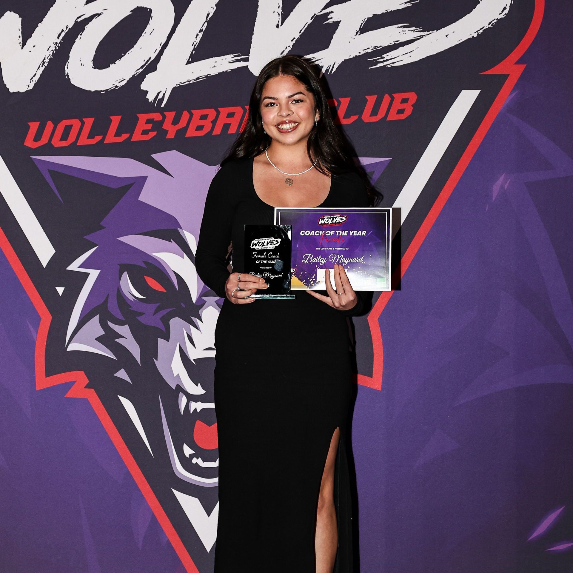 A woman in a black dress is holding a certificate in front of a volleyball club logo