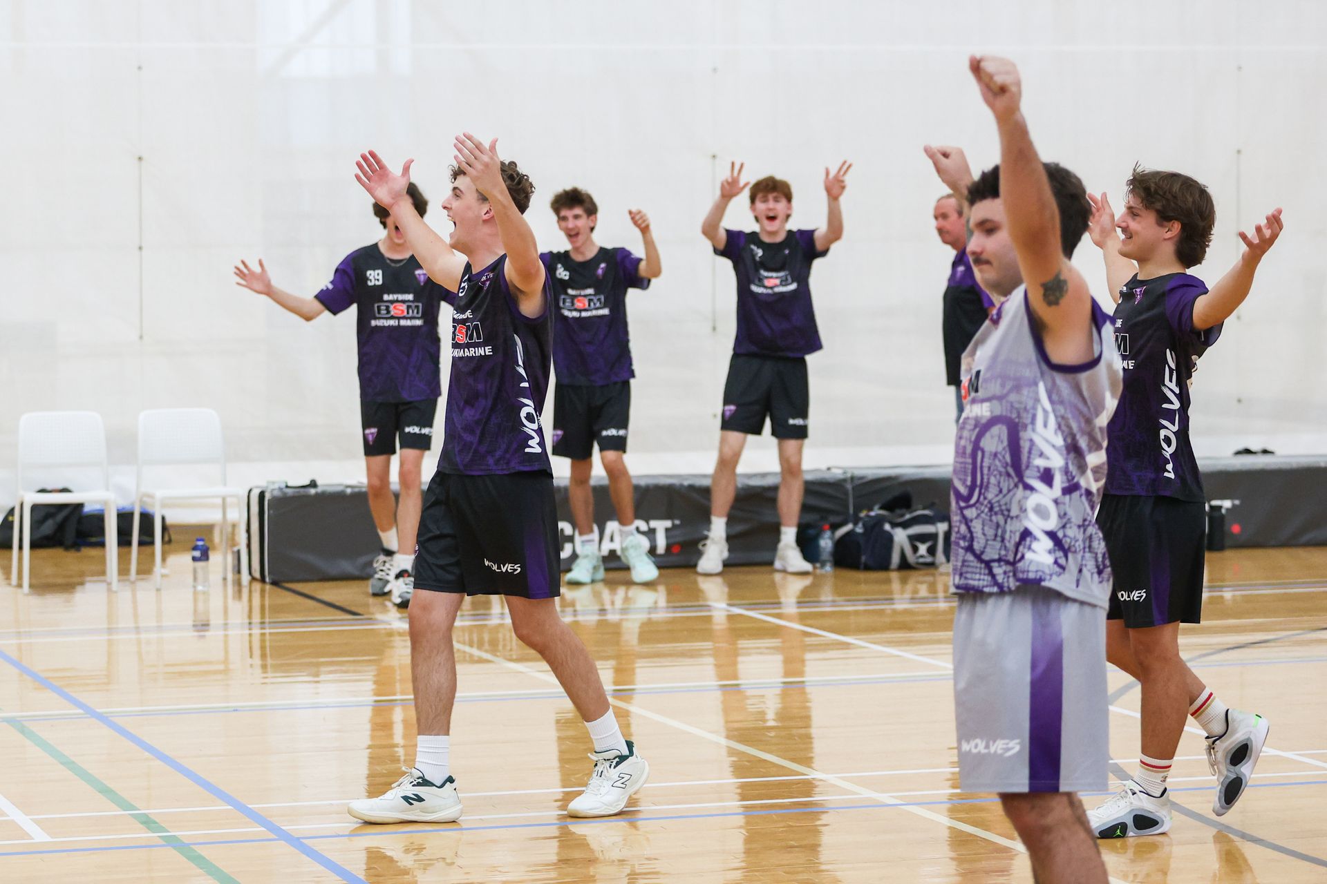 A group of girls are playing volleyball in a gym.