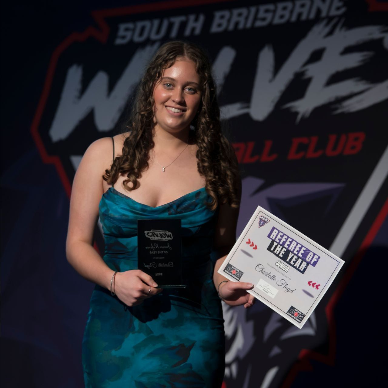 A woman in a blue dress is holding a certificate that says beefbeef of the year