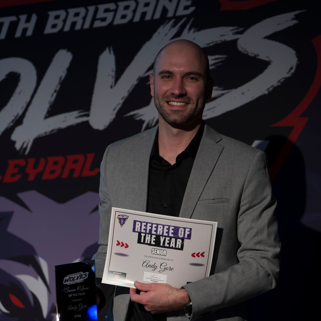 A man holding a certificate that says referee of the year