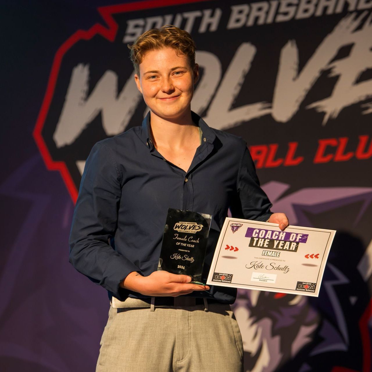 A man holding a certificate that says coach of the year