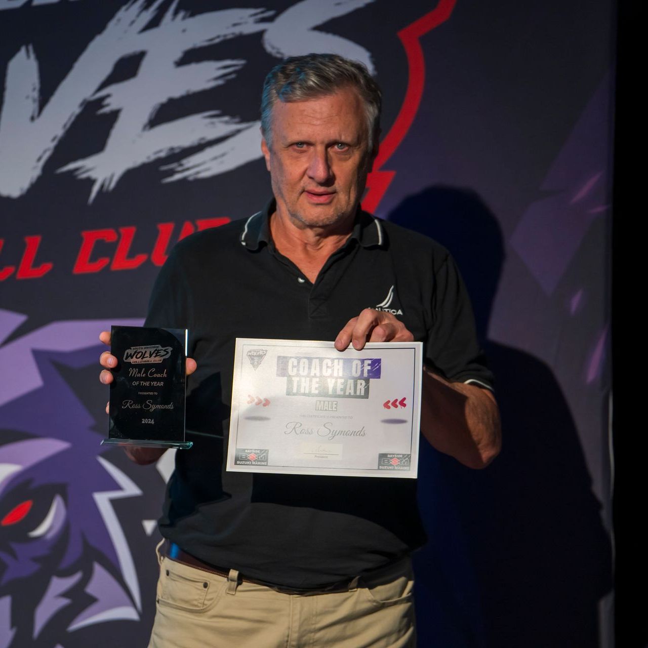 A man is holding a certificate that says coach of the year