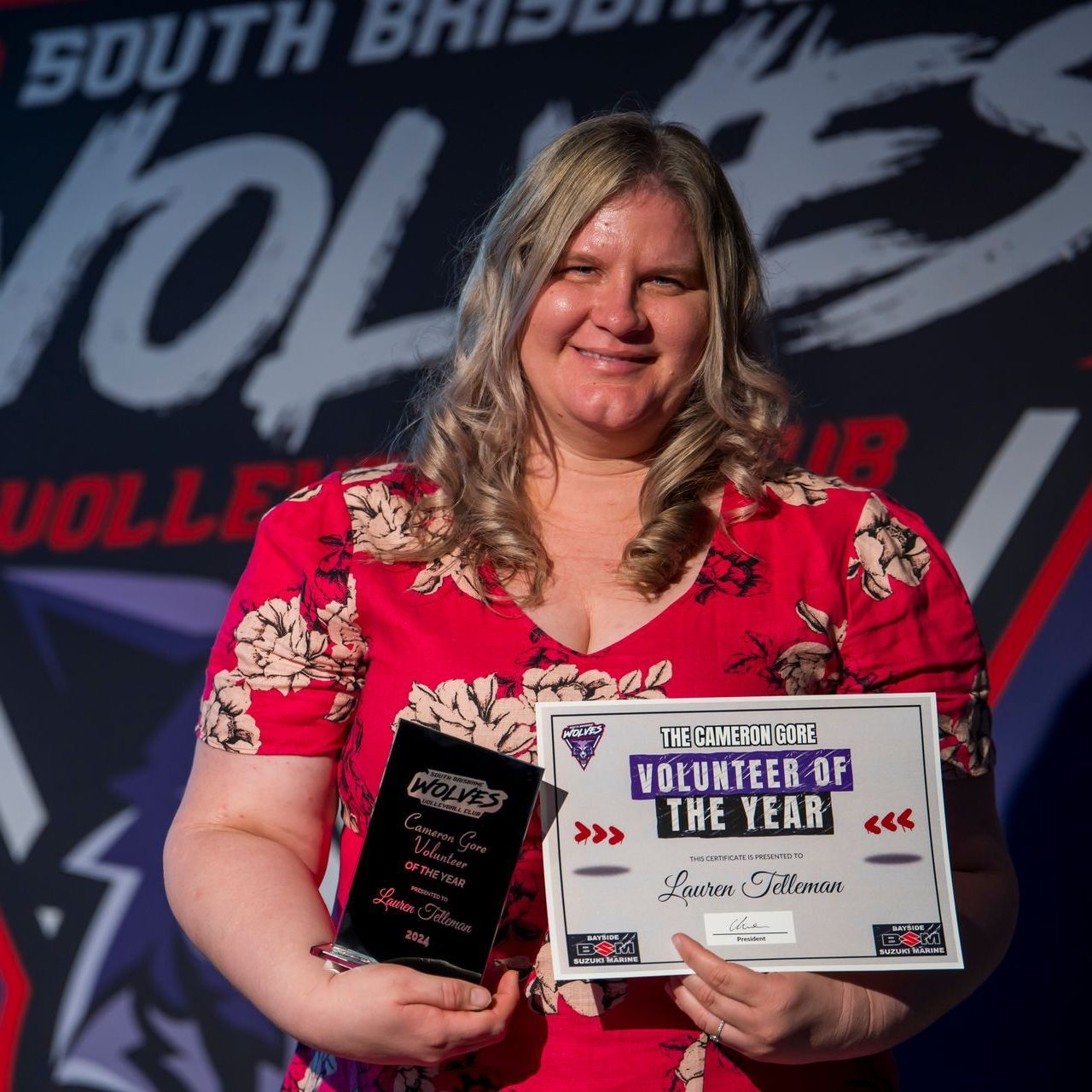 A woman is holding a certificate that says volunteer of the year