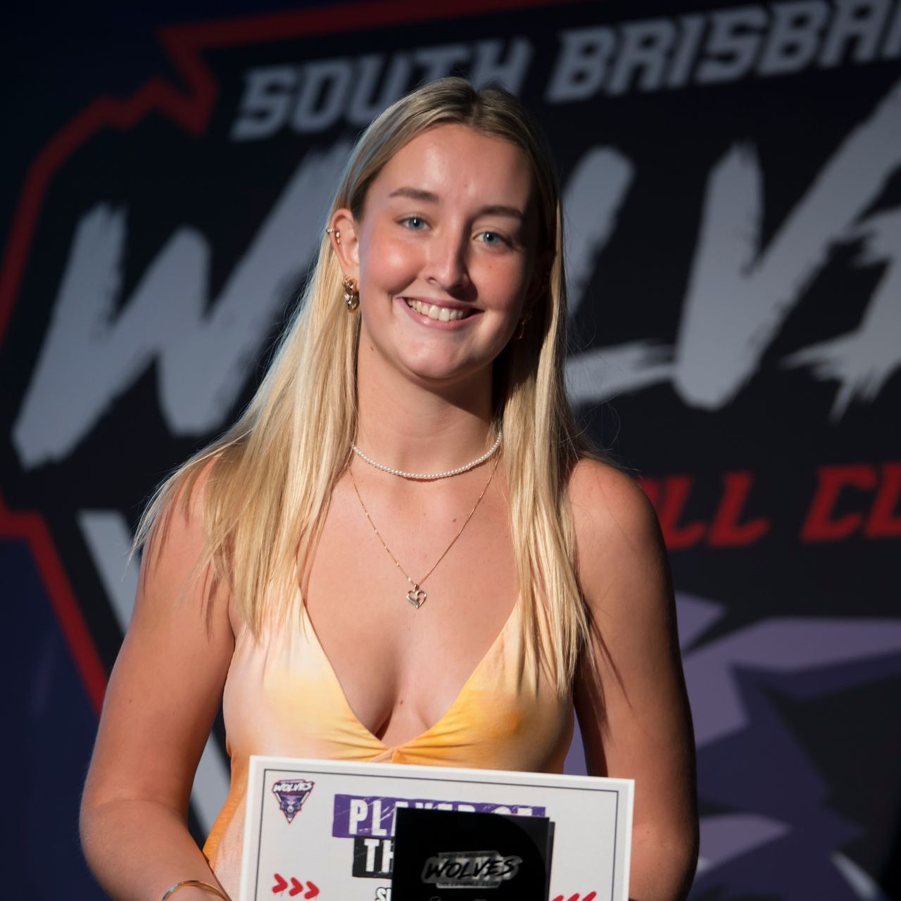 A woman is holding a certificate in front of a sign that says south brisbane