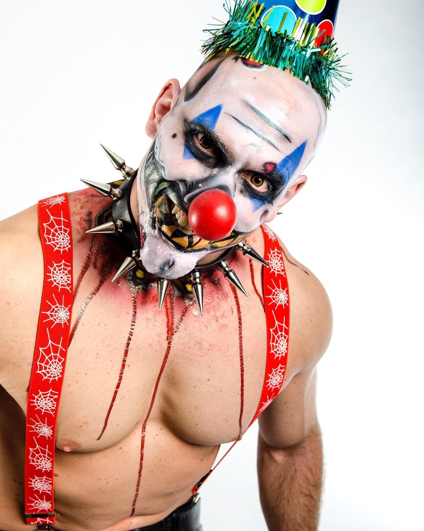 Un homme déguisé en clown avec un nez rouge et des bretelles