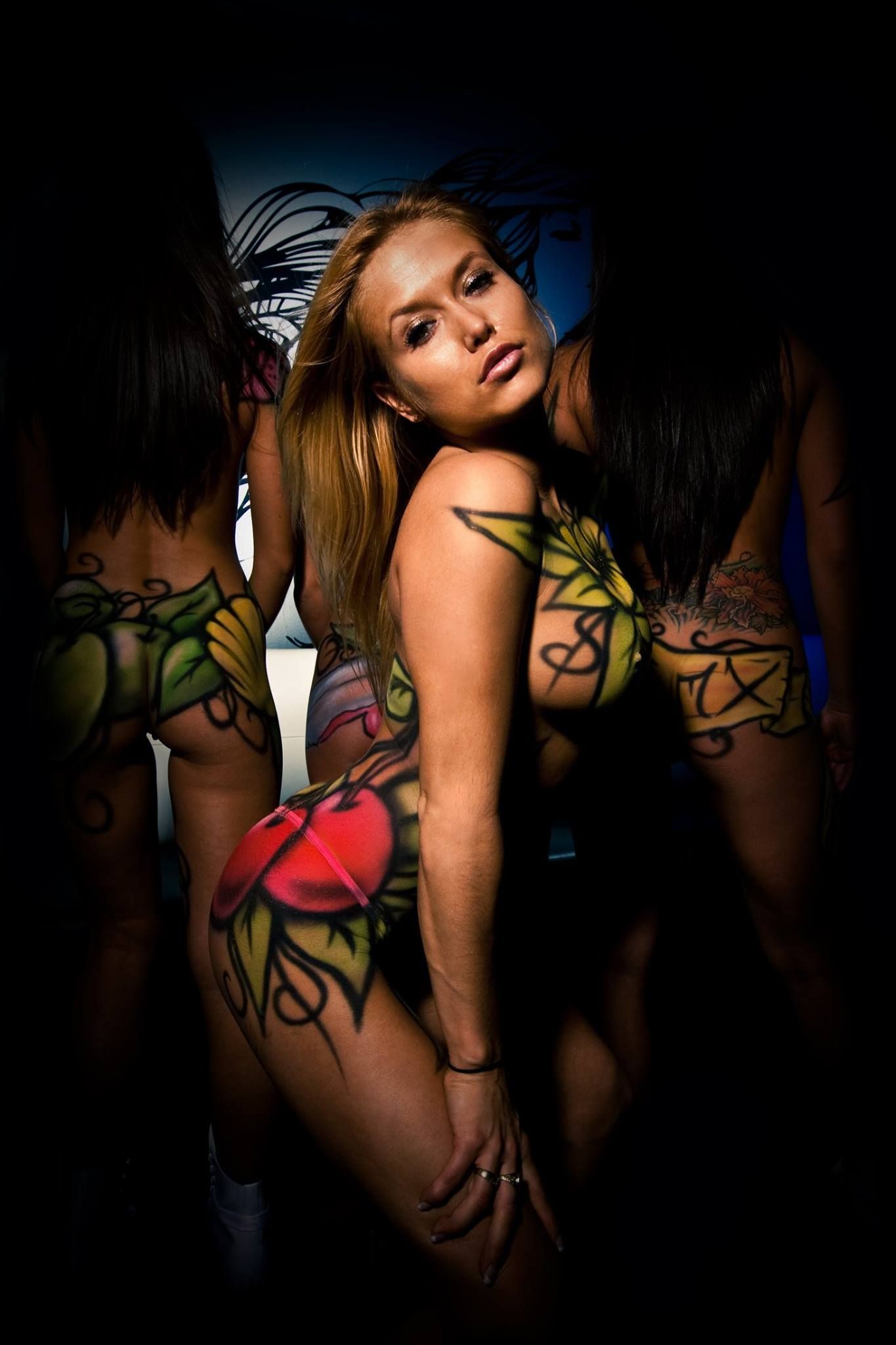 Trois femmes se tiennent côte à côte, leurs corps peints.