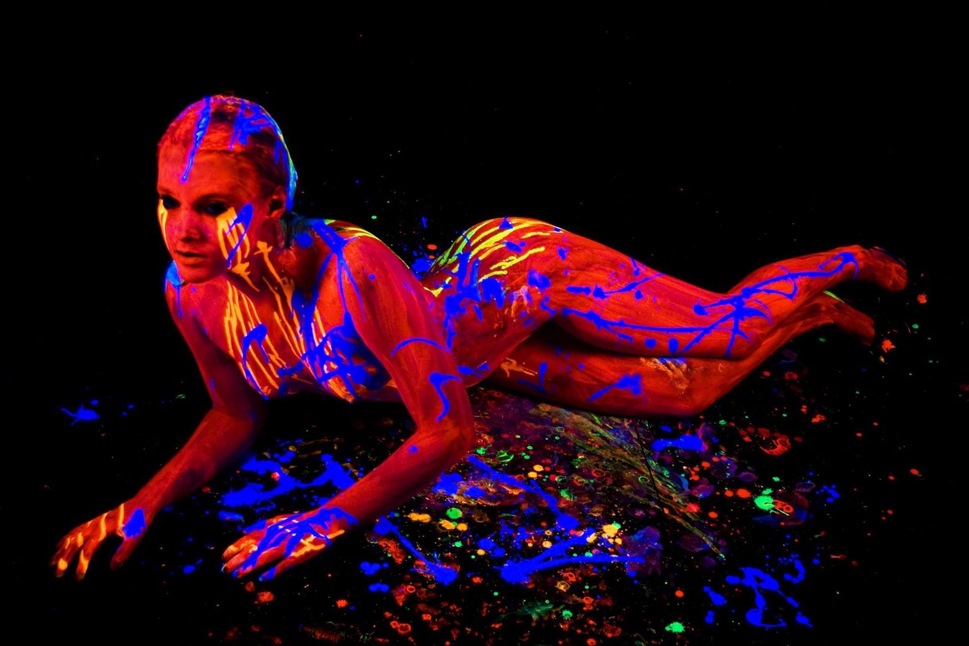 Une femme est allongée sur le sol avec de la peinture phosphorescente sur son corps.
