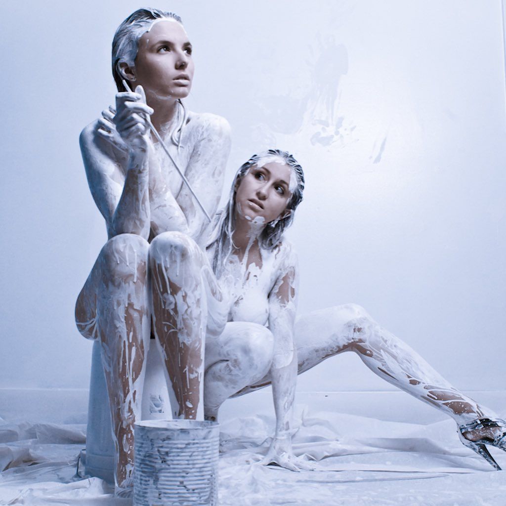 Deux femmes recouvertes de peinture blanche sont assises l'une à côté de l'autre