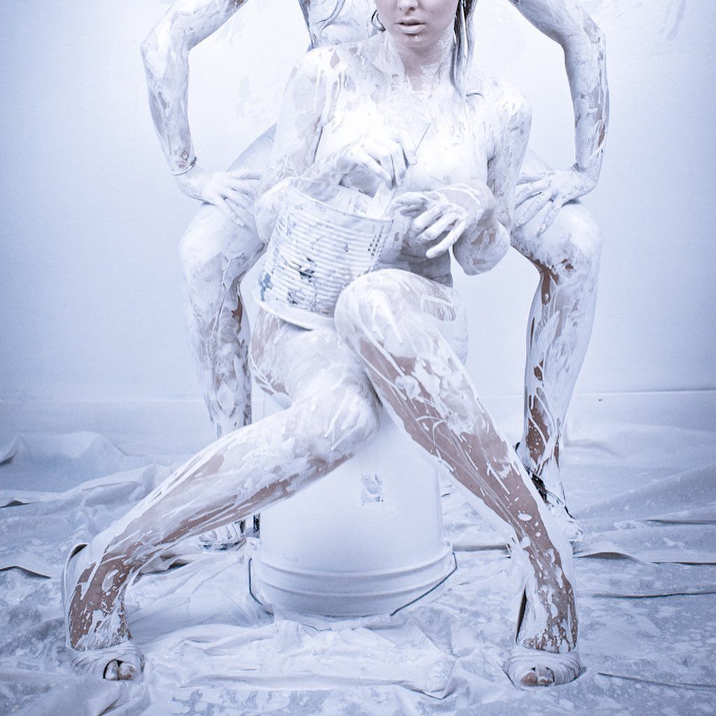 Une femme recouverte de peinture blanche est assise sur un seau