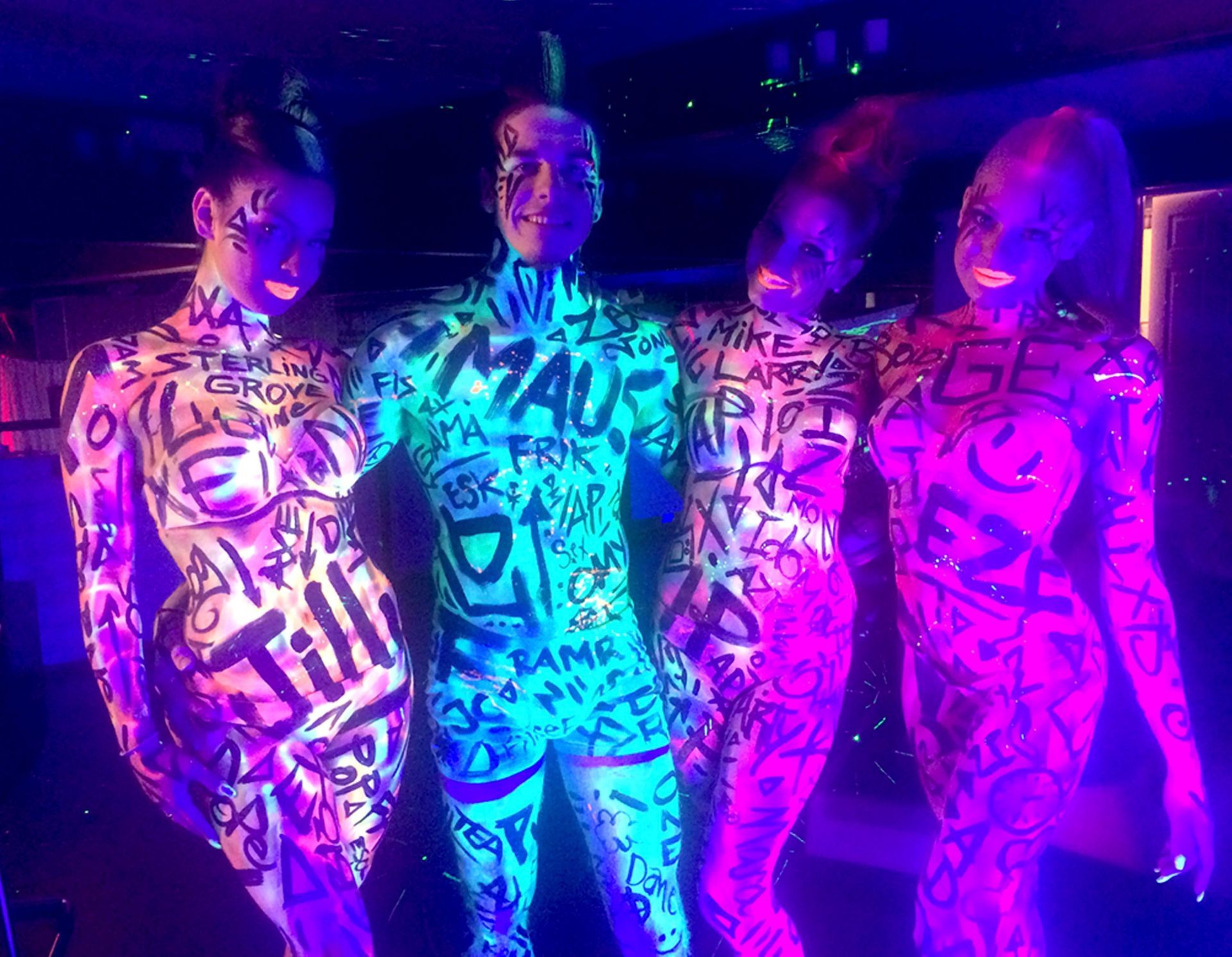 Un groupe de personnes se tiennent côte à côte, leurs corps peints de graffitis.