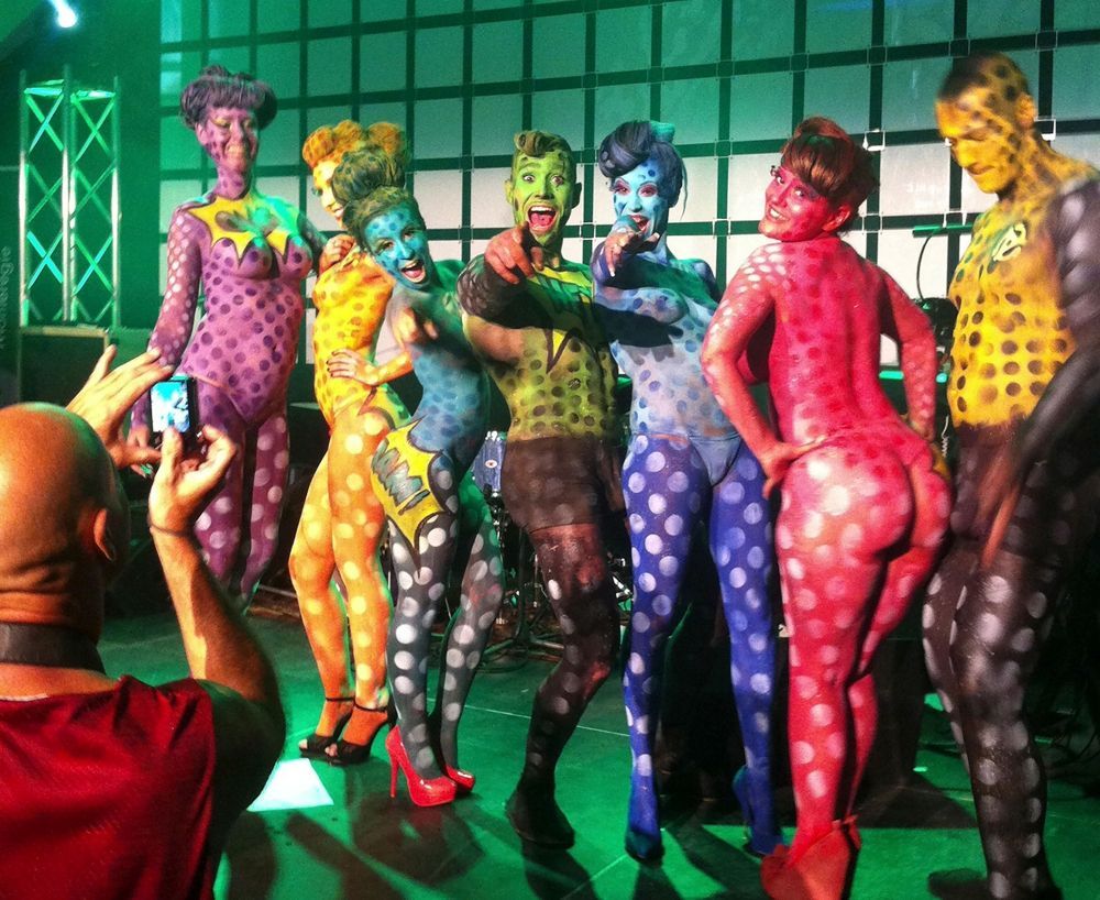 Un homme prend une photo d'un groupe de personnes peintes de différentes couleurs