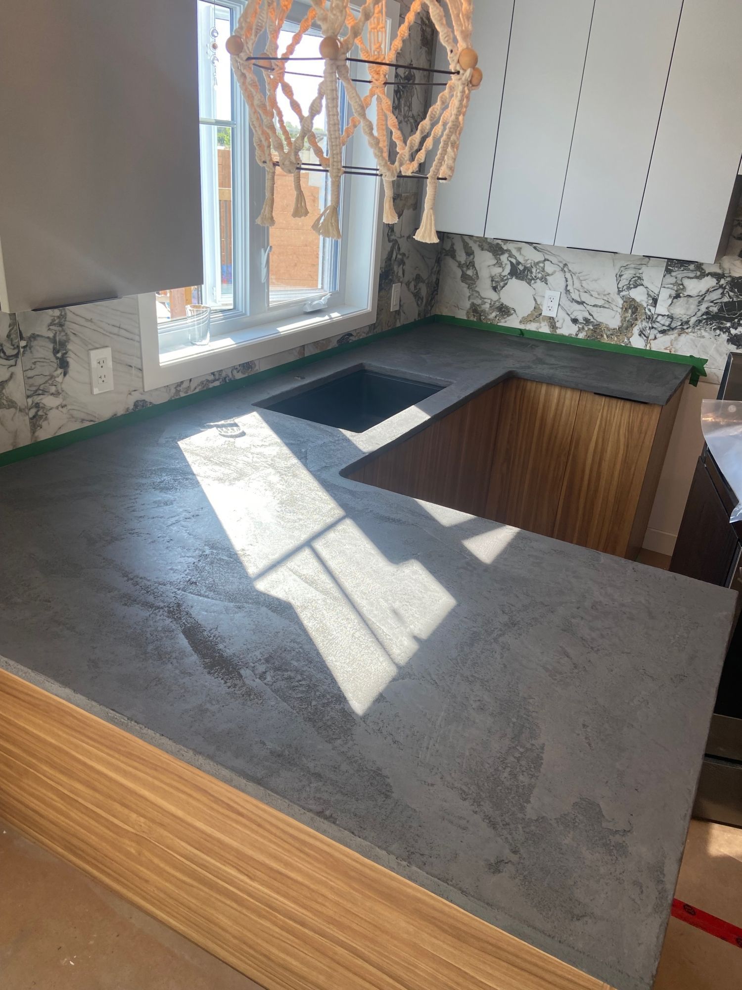 Une cuisine avec un comptoir en béton et un évier.