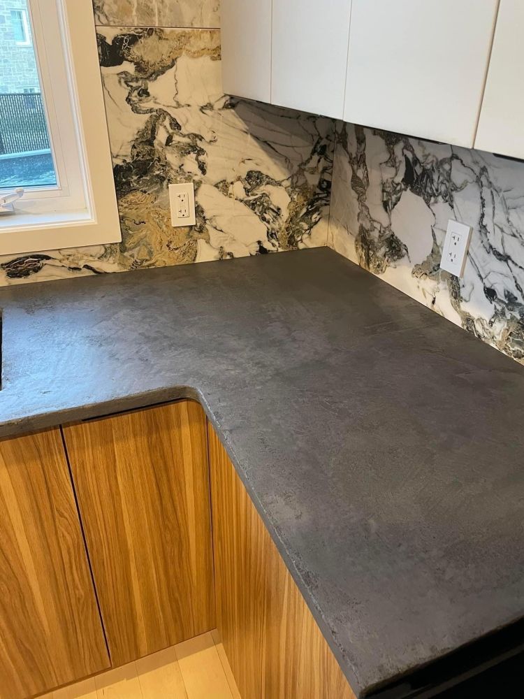 Une cuisine avec un comptoir noir et des armoires en bois.