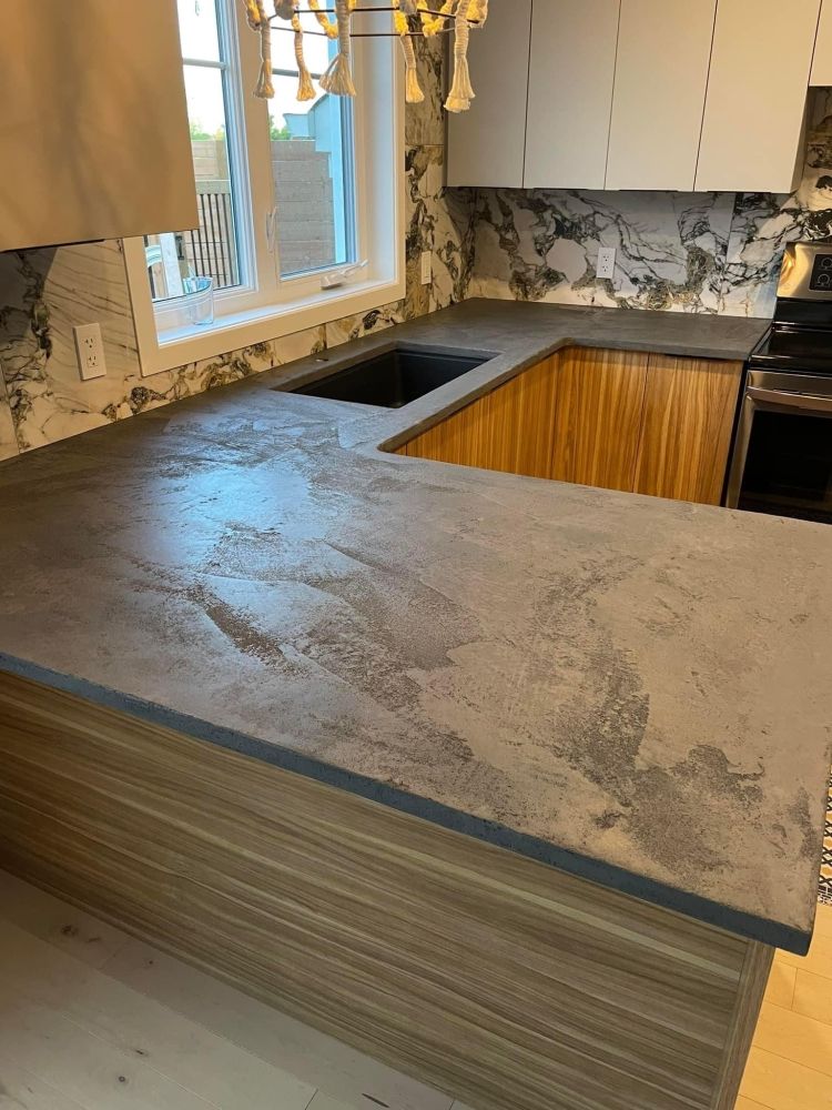 Une cuisine avec un comptoir en béton et un évier.