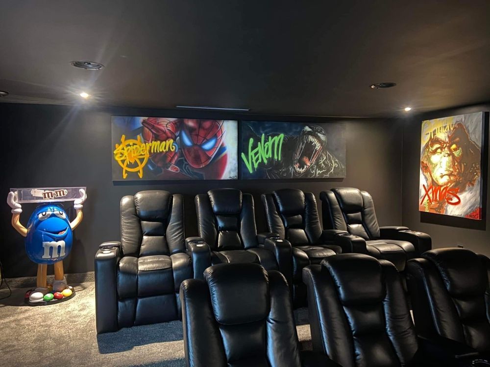 Un home cinéma avec sièges en cuir noir et statue am&m.