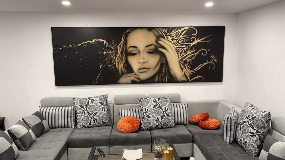 Un salon avec un canapé et un tableau d'une femme sur le mur.