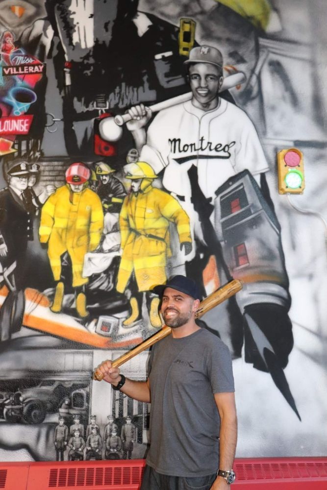 Un homme tenant une batte devant une murale de Montréal