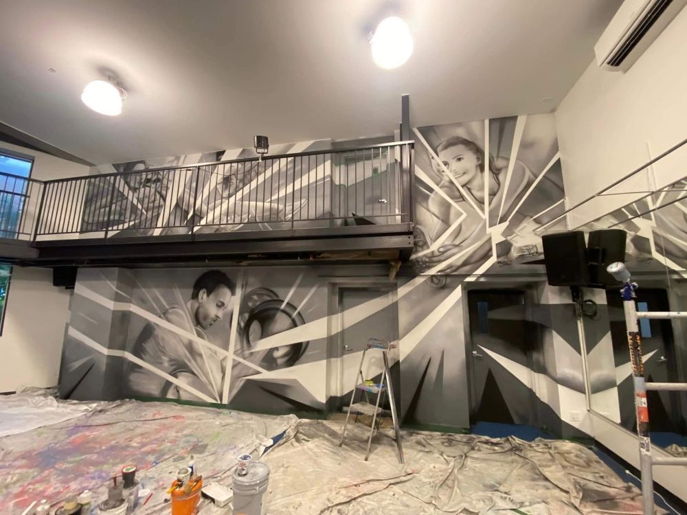 Une grande fresque est en train d'être peinte sur le mur d'une pièce.