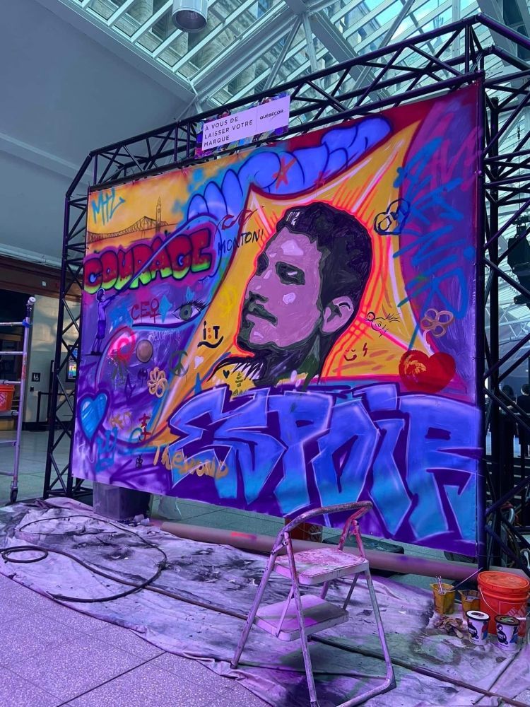 Un grand graffiti représentant un homme est en train d'être peint sur un mur.