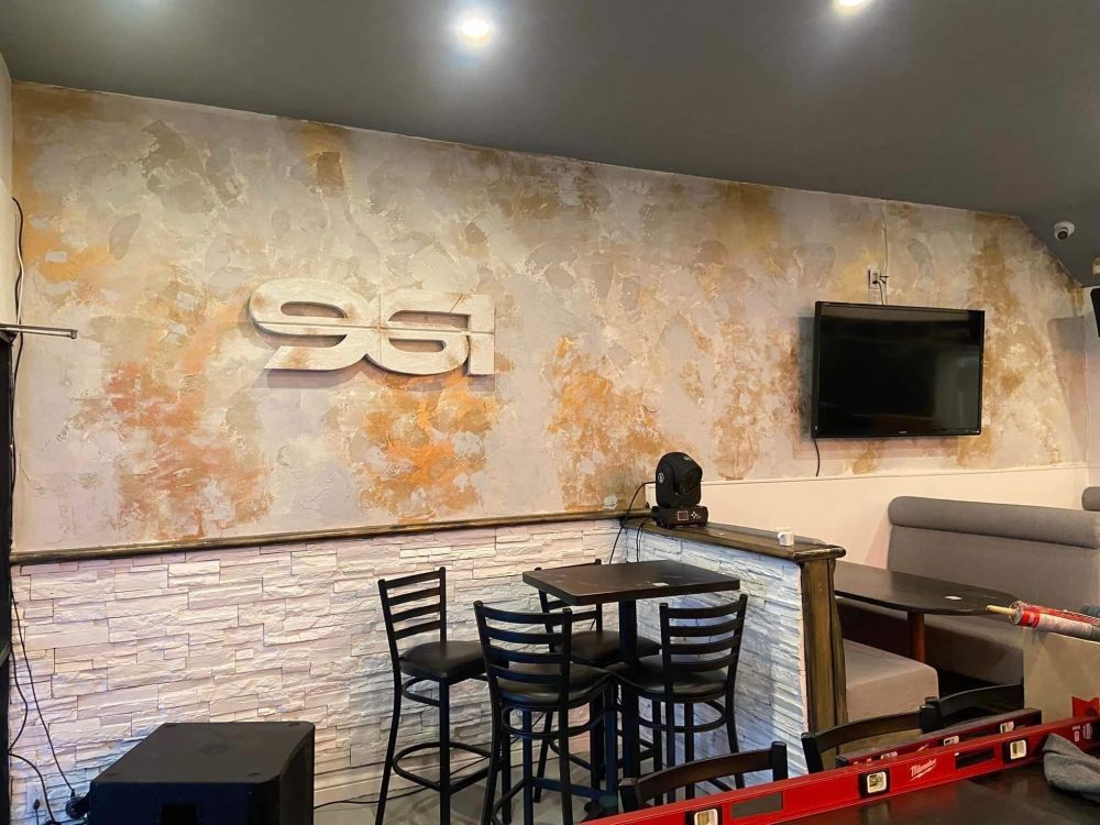 Un restaurant avec des tables et des chaises et une télévision au mur.