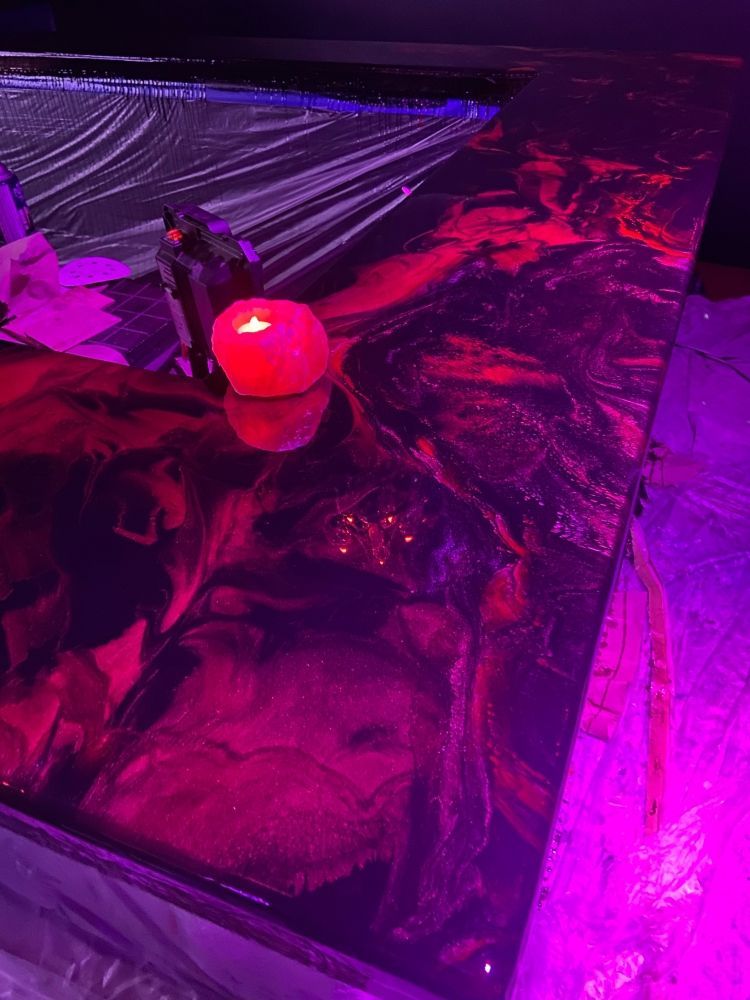 Une bougie est posée sur une table sous une lumière violette.