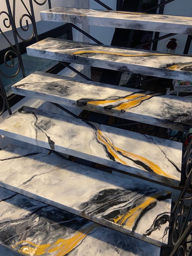 Un gros plan d'un escalier avec des marches en marbre et une rampe en fer forgé.